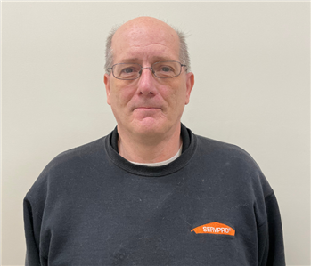 Man with glasses with SERVPRO sweater against a light gray background